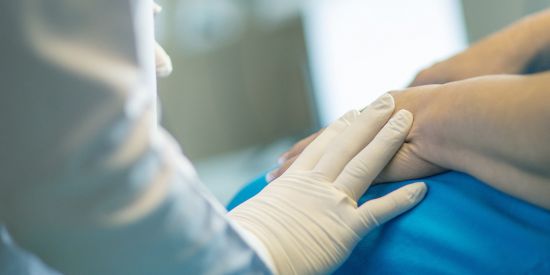 health care worker with gloved hand holding patient hand