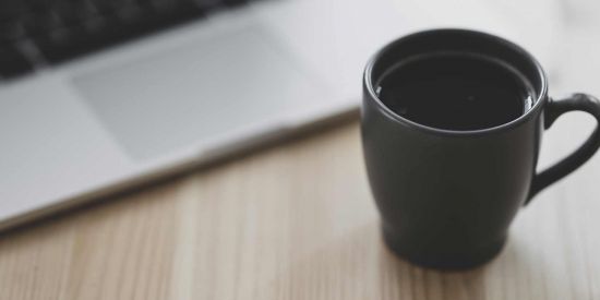 cup of coffee by a laptop on a table