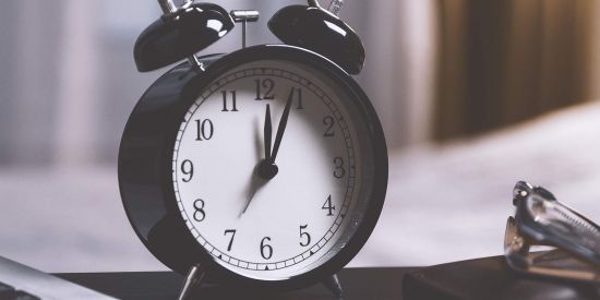 black alarm clock with bells on a desk