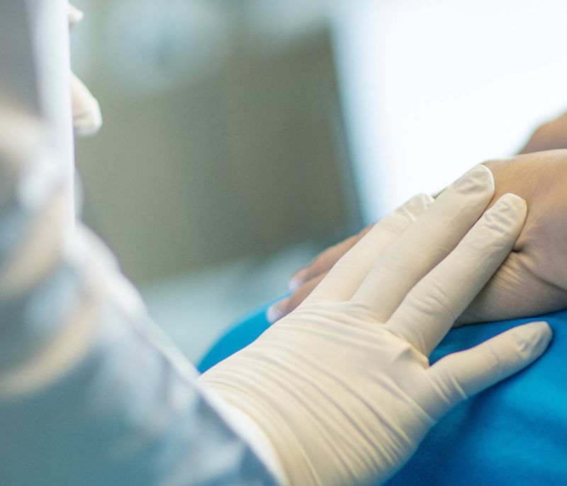 health care worker with gloved hand holding patient hand