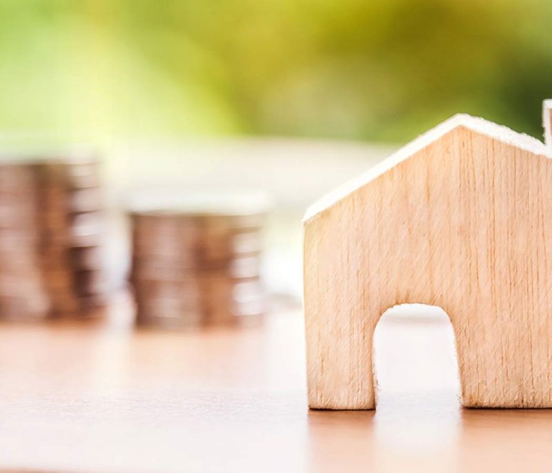 wooden block house with coins in the background