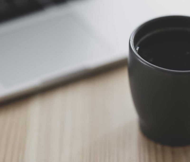 cup of coffee by a laptop on a table